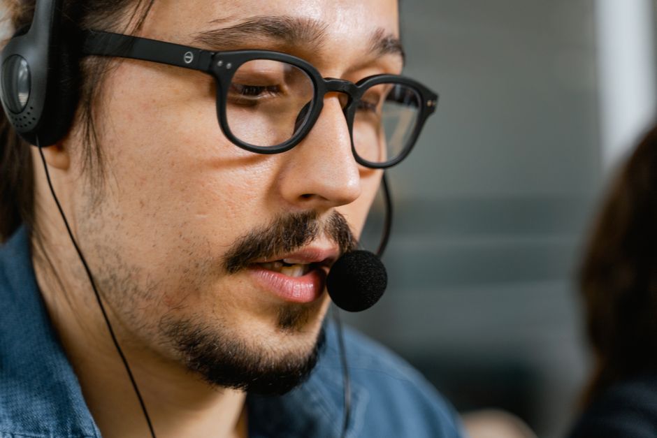 Aproximação de um agente de call center com headset e óculos fornecendo suporte ao cliente.