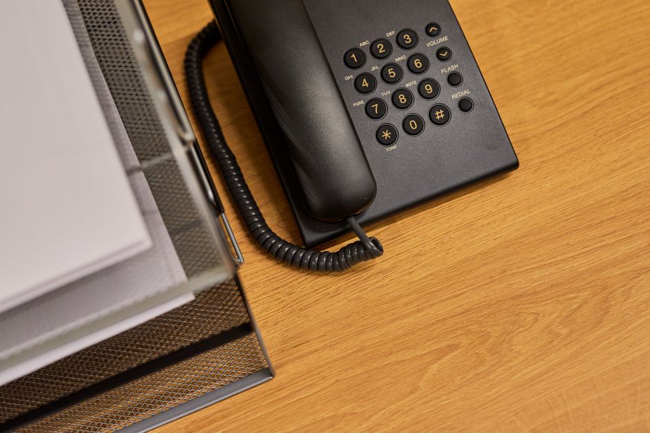 Uma mesa de escritório arrumada com um telefone preto clássico e documentos organizados.