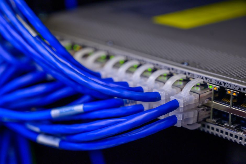 Vista detalhada de cabos ethernet azuis conectados a um switch de rede em um data center.