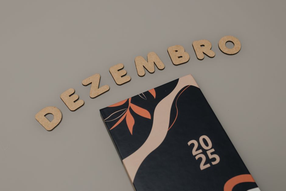 Um calendário minimalista de 2025 com letras de cortiça formando "DEZEMBRO" em um fundo neutro.