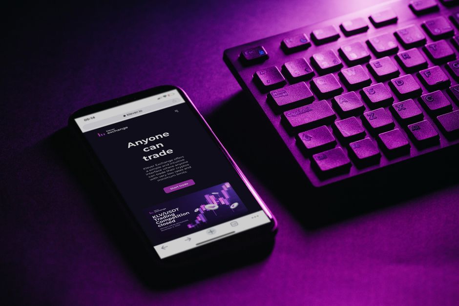 Close-up de um smartphone e teclado com um tom roxo, representando tecnologia moderna e conectividade.