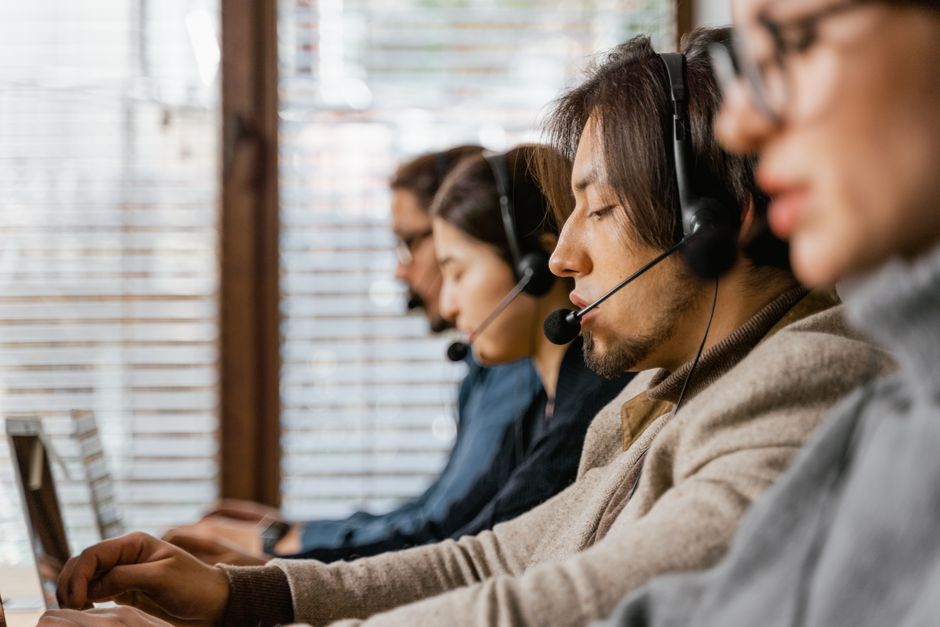 Funcionários de call center trabalhando diligentemente com headsets, oferecendo atendimento ao cliente dedicado.